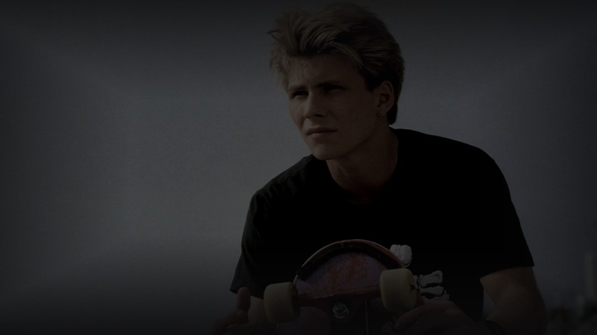 Still from Gleaming the Cube (1989) — tmdb backdrop, christian slater with skateboard, pre-darkened 0.60, baked at factor 0.45, downsized to 1200x675, output brightness 33.4